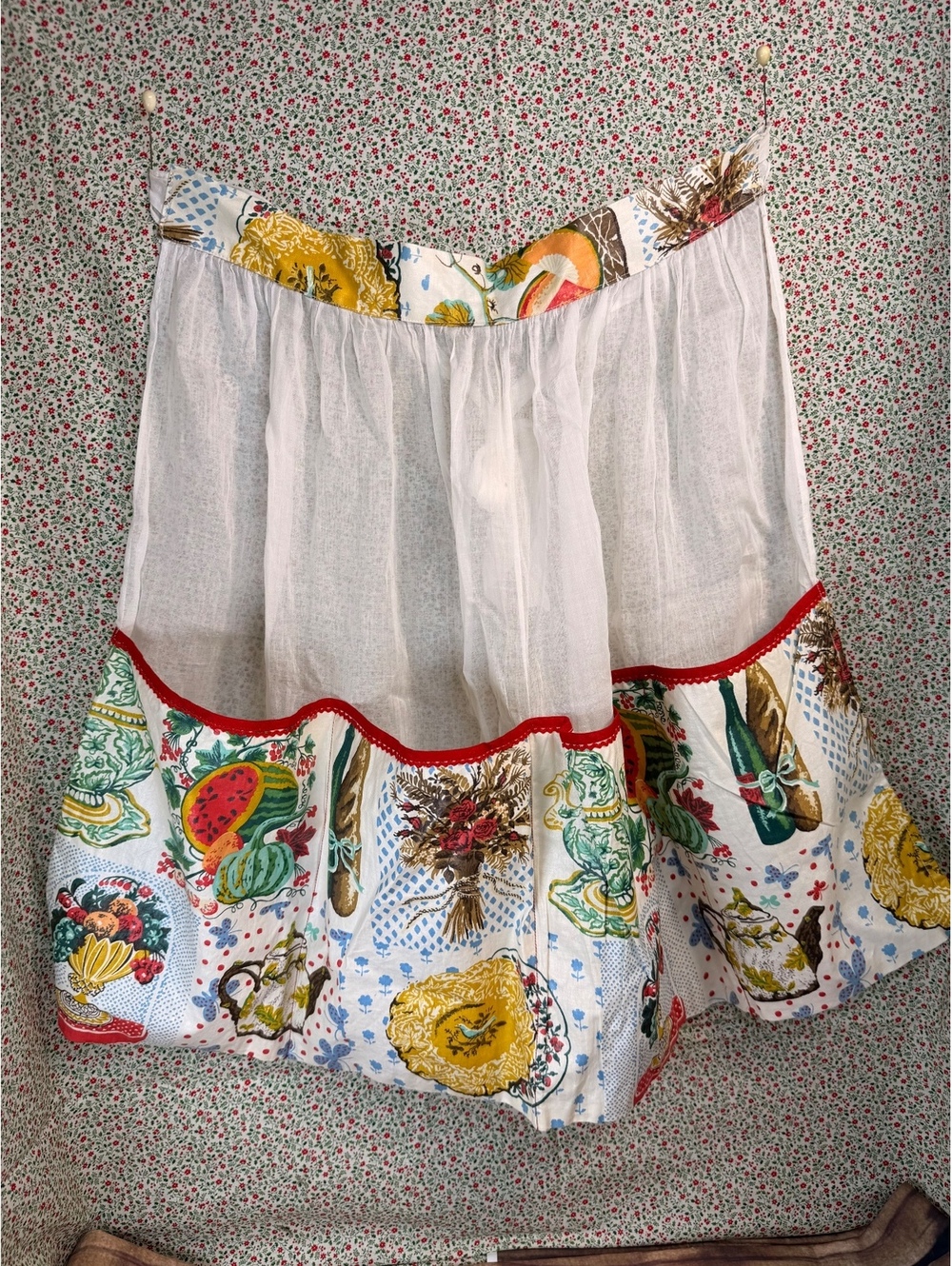 White floral apron with red trim